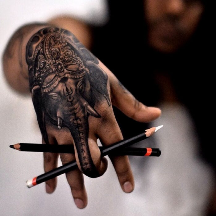 mano con tatuaje de un elefante y la trompa en el dedo medio 