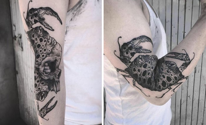 tatuaje en un brazo que doblado forma un cangrejo y desdoblado forma un cráneo 