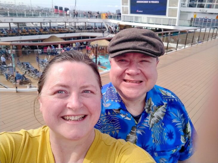 Selfie de una pareja frente a una embarcación en el mar 