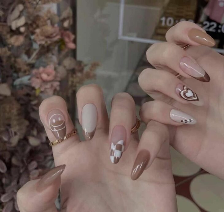 uñas acrílicas en colores cafés con dibujos en varias uñas 