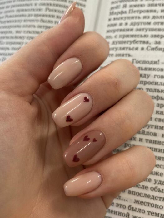 Nude nails with a brown nail and heart designs 