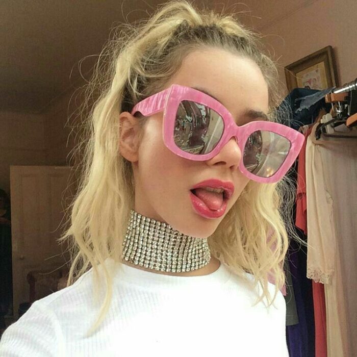 chica usando unas gafas de sol en color rosa grandes 