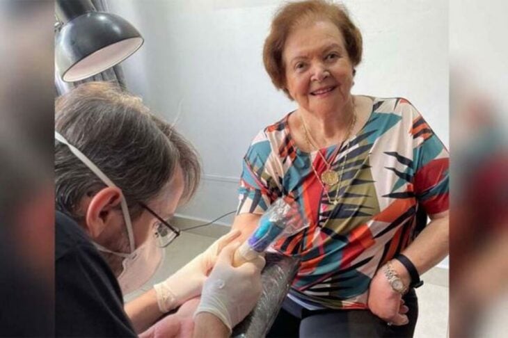 foto de un tatuador haciendo un tatuaje a una adulta mayor 