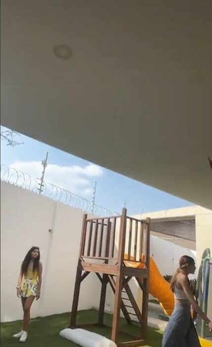 imagen que muestra a dos chicas alrededor de un pequeño jardín con juegos para niños en una casa 