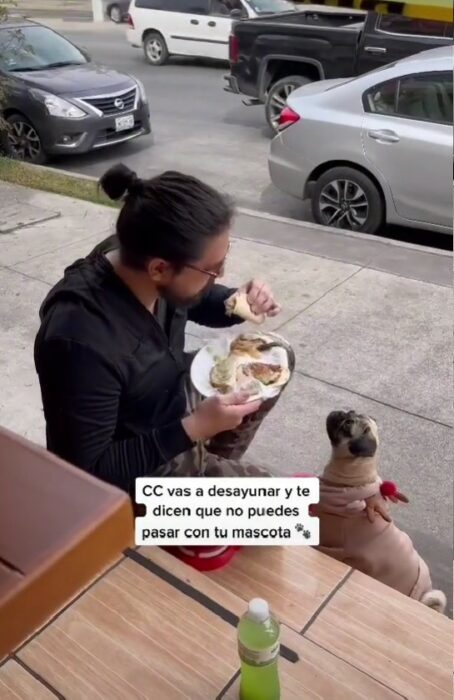 hombre comiendo afuera de un restaurante con su perro 