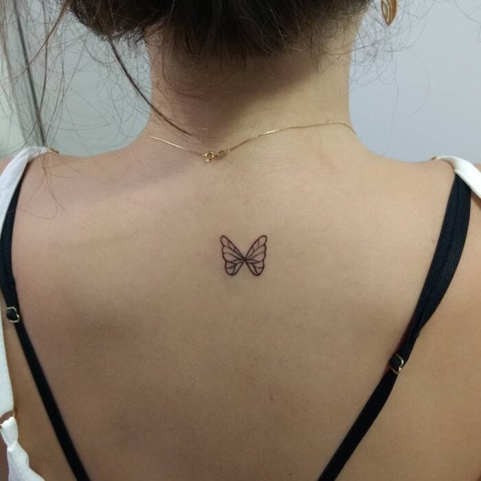 espalda de una chica mostrando un tatuaje mini de mariposa