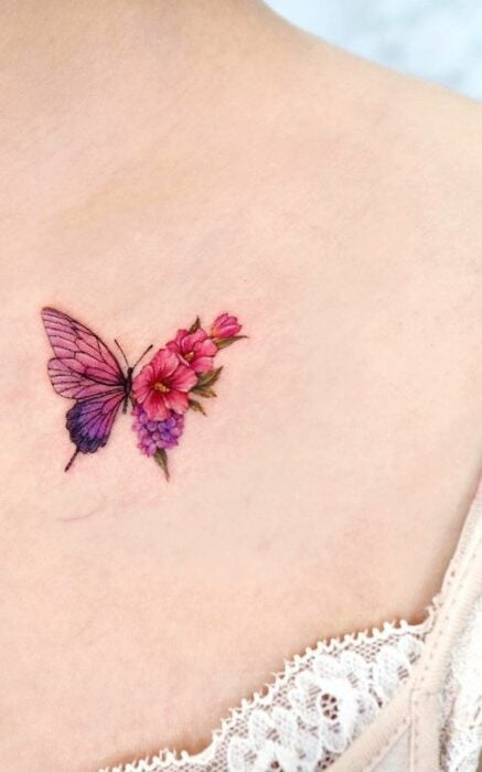 tatuaje de mariposa complementado con unas flores rosas en el pecho de una chica 