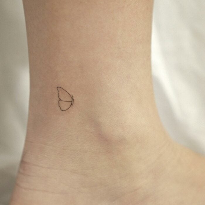 mini tatuaje en forma de mariposa en el tobillo de una persona 