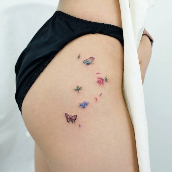 tatuaje de una mujer con mariposas y flores de colores 
