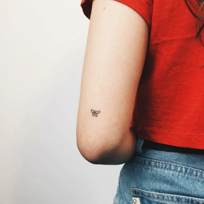 codo de una chica con un pequeño tatuaje de mariposa 