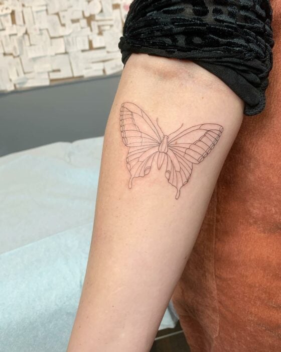 tatuaje de mariposa minimalista en el antebrazo de una persona 
