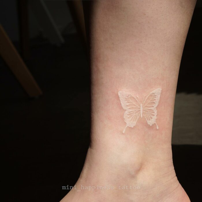 Tatuaje de mariposa blanca cerca de la muñeca de una mujer 