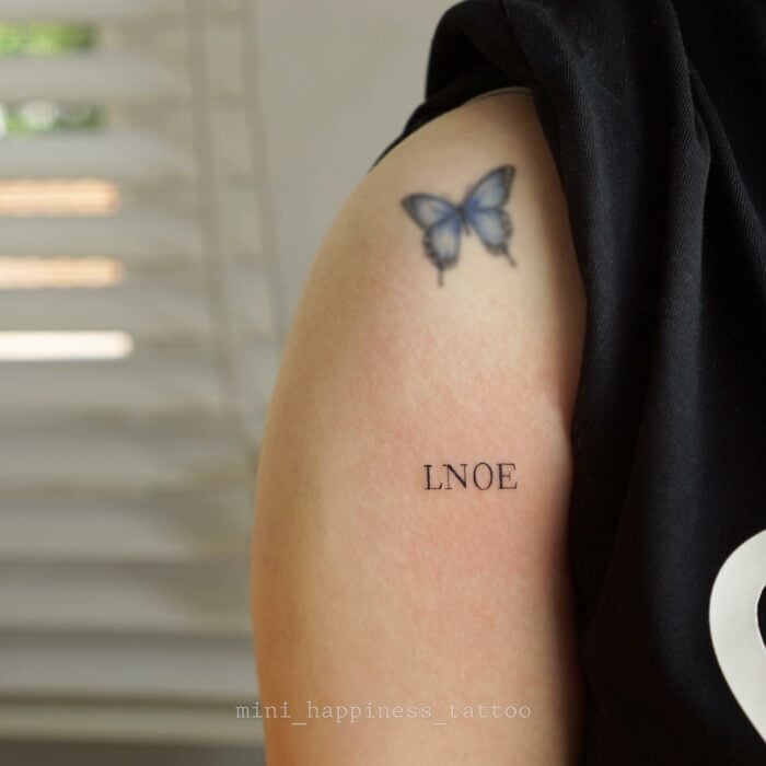 tatuaje de mariposa de color azul en el hombro de una mujer 