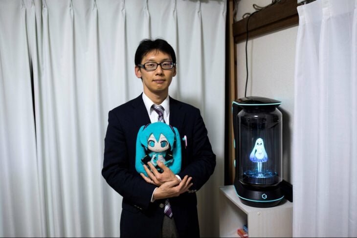 Akihiko Kondo posando a lado de su esposa el holograma de la primer cantante virtual japonesa 