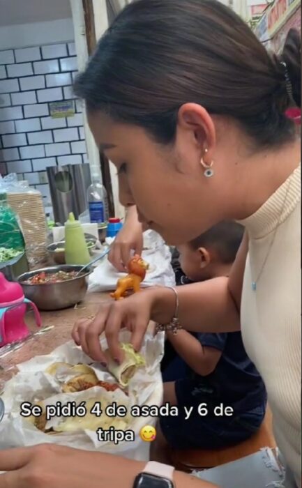 image of a girl eating tacos at a stand inside the market 