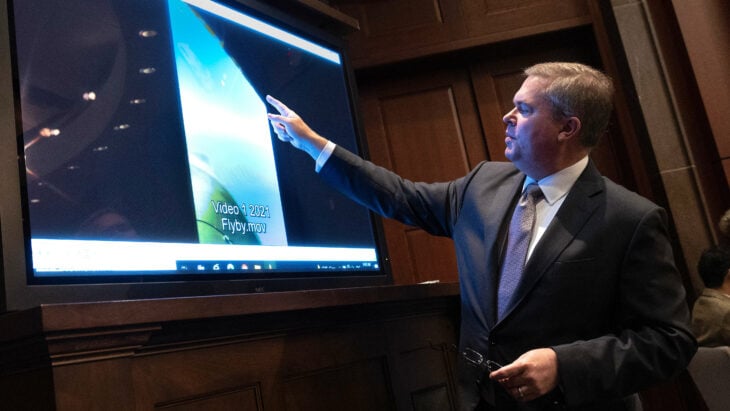 Hombre apuntando hacía una pantalla durante una reunión 