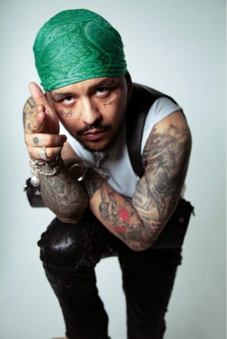 Foto del cantante Nodal con un paliacate verde sobre su cabeza mirando hacia enfrente 