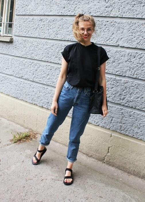 chica con jeans y playera negra usando sandalias deportivas