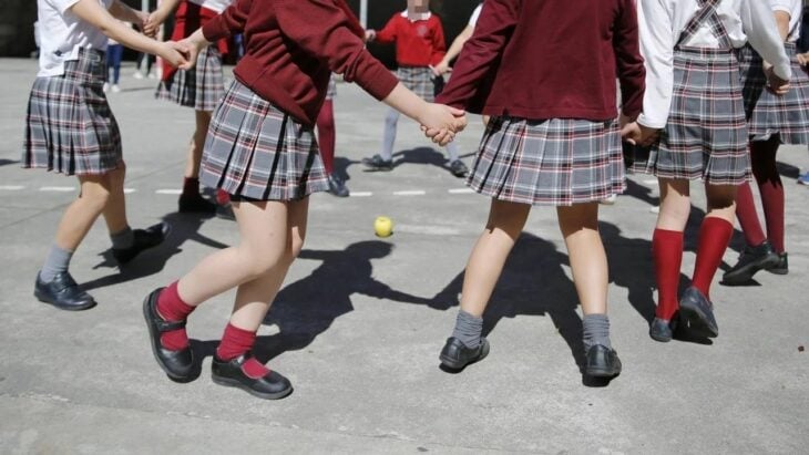 Grupo de niños con uniformes escolares jugando en el patio de la escuela 