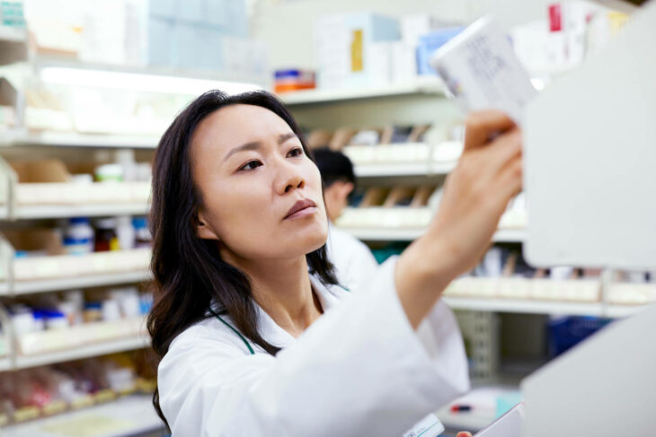 Mujer farmacéutica arreglando medicamentos en el estante