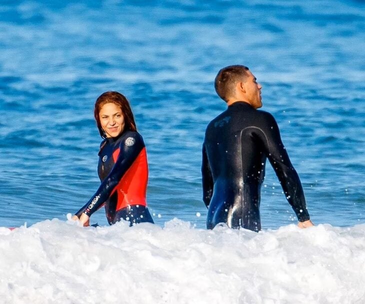 Shakira and a man surfing