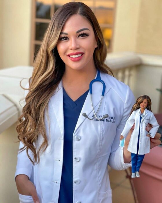 Doctora con una muñeca Barbie en su mano 