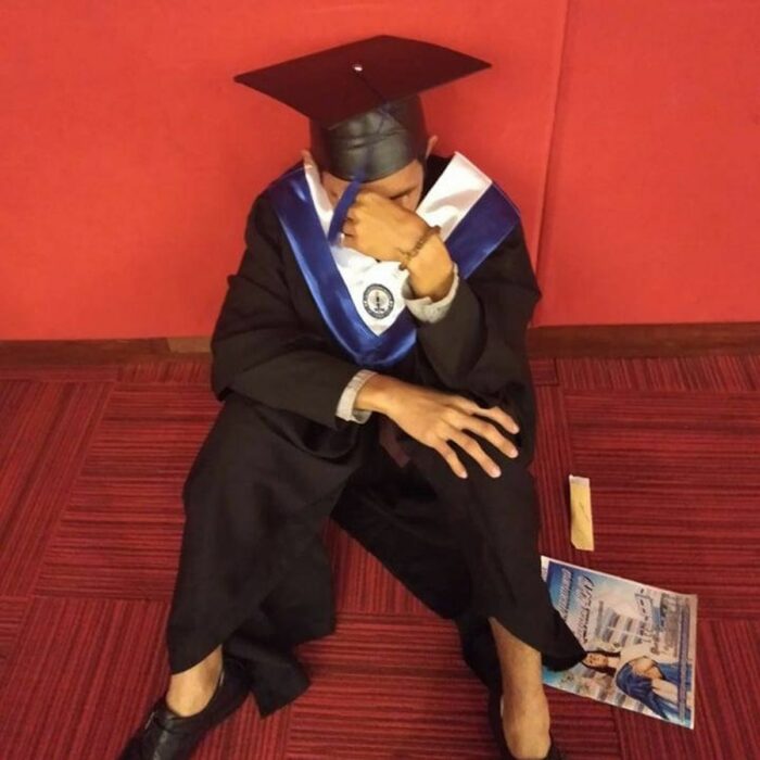 Chico recién graduado sentado en el suelo llorando porque su familia lo dejó solo 