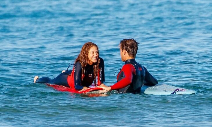 Shakira and a man surfing