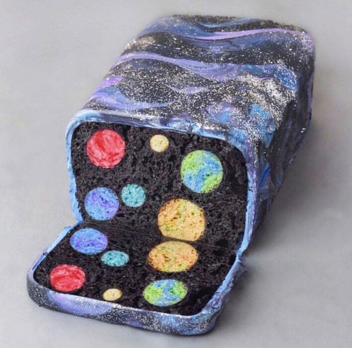 pastel que muestra en su interior figuras de planetas de colores 