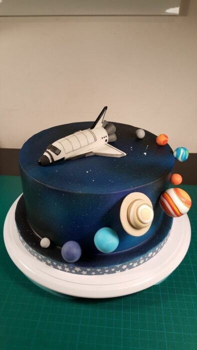 pastel galáctico con algunas figuras de planetas y una nave encima 