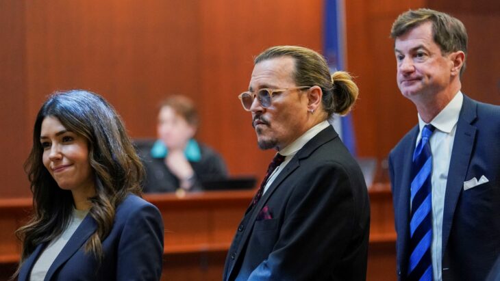 Johnny Depp parado en medio de sus dos abogados en el juicio por difamación contra Amber Heard