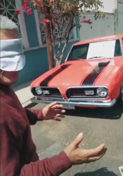 imagen que muestra a un hombre con los ojos vendados frente a un coche rojo 