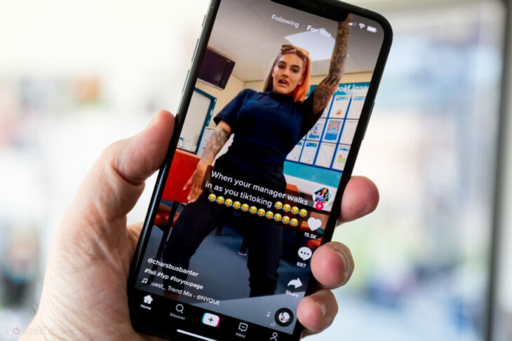 mano sosteniendo un celular mientras ve a una mujer bailando en TikTok 