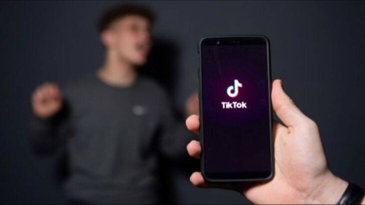 celular con el logotipo de TikTok y una persona bailando detrás