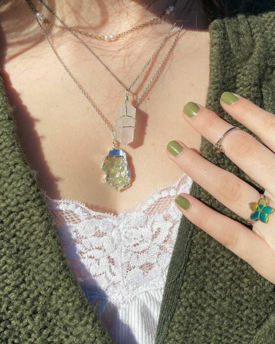 chest of a woman showing two necklaces with green quartz 