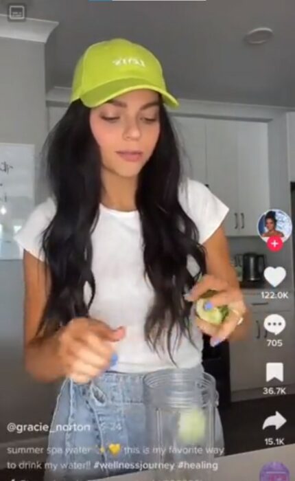 chica estadounidense preparando agua de spa con pepino 