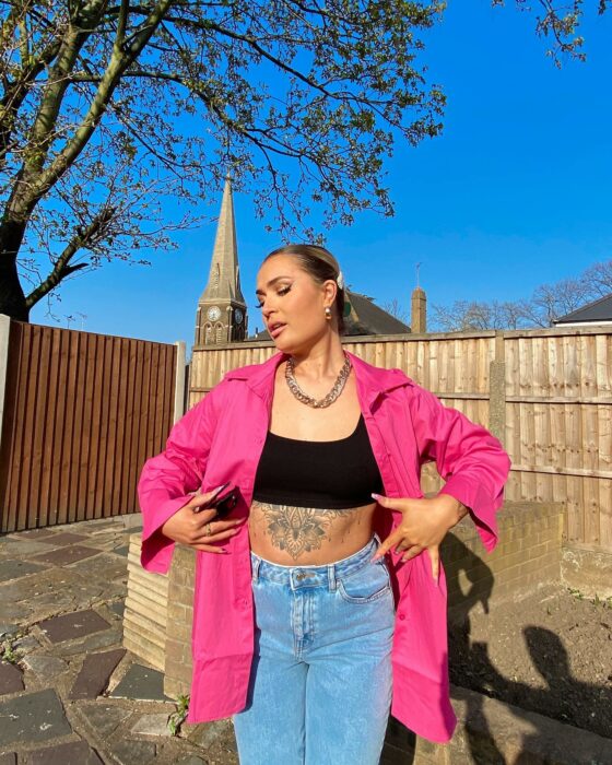 fotografía de una chica posando frente al sol con un top en color negro con un saco en color rosa 