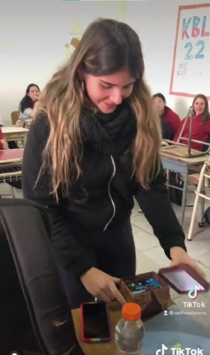 i9shot of a girl opening a present from a classmate