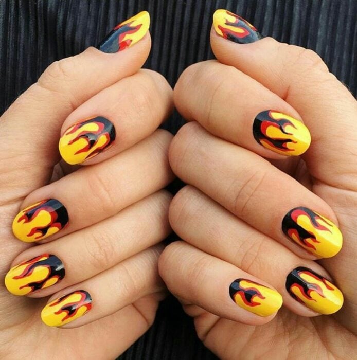 manos mostrando un diseño on fire en uñas cortitas 