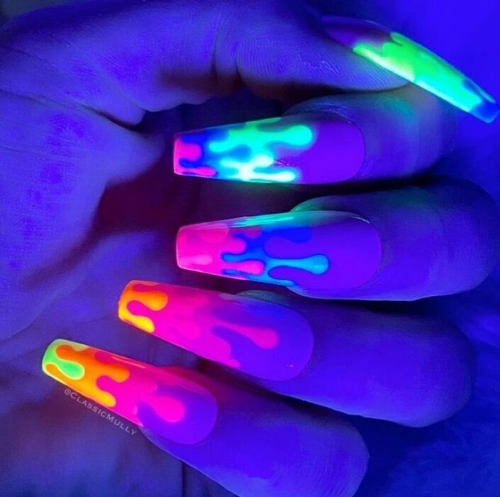 mano de una chica con uñas acrílicas que brillan en la oscuridad 