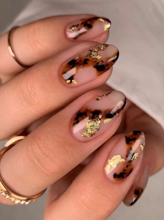 hands showing nail design in brown with black and gold foil 