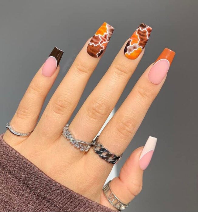 mano mostrando el diseño de uñas con efecto rompecabezas en colores cafés y naranjas 