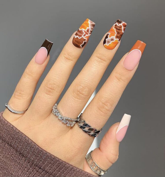 hand showing puzzle effect nail design in brown and orange colors 