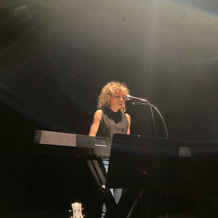 Jennette McCurdy tocando el piano en un escenario 