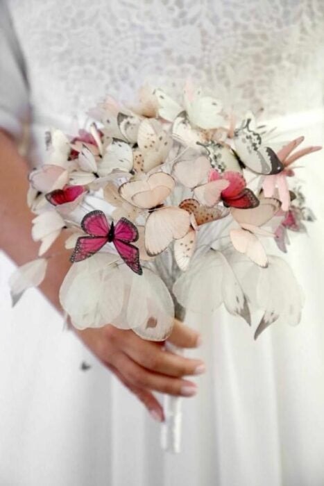 novia agarrando un ramo hecho con mariposas en colores pastel 