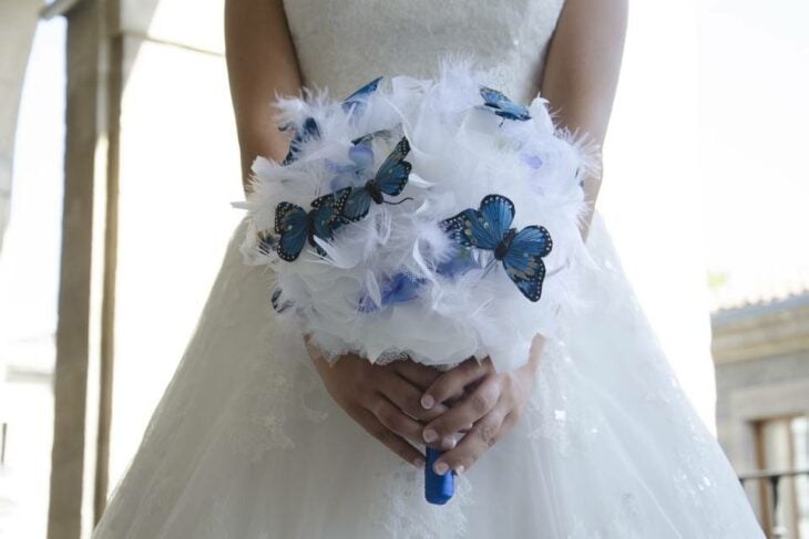 novia con un ramo blanco combinado con mariposas en tonos azules 