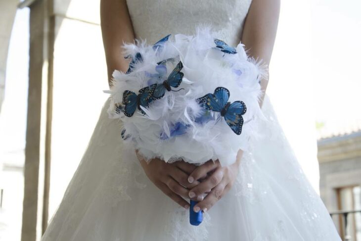 novia con un ramo blanco combinado con mariposas en tonos azules 