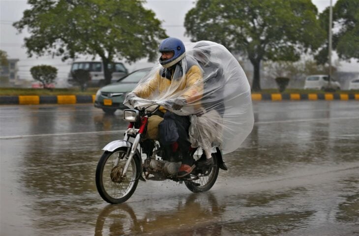 Dos individuos en moto con una bolsa de plástico como impermeable