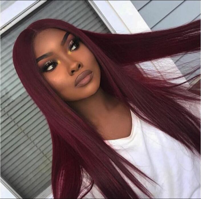 photo of a model with dark skin showing off her long wine-colored hair 