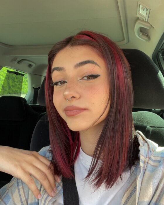selfie of a girl with wine-colored highlights in her car 